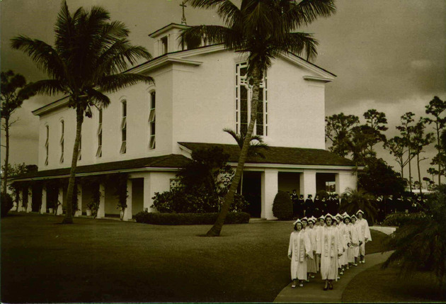 College students wearing academic formal attire leave Chapel in procession